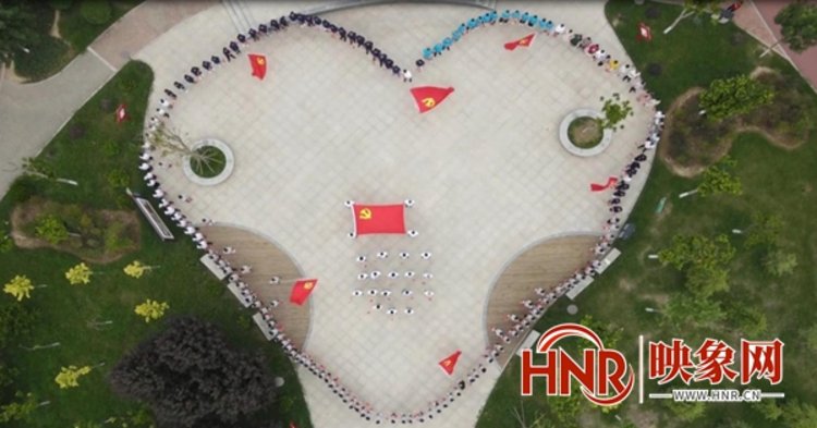 五百多名党员干部,企业员工集聚在一起围成心形,面对党旗,举起右臂