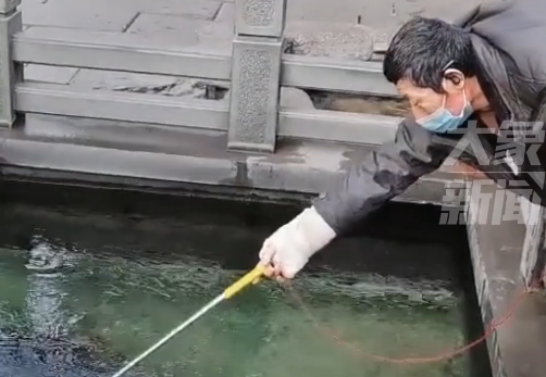 大爷用自制工具从许愿池里捞硬币