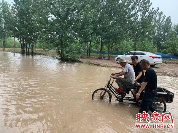 郑州一名骑三轮车老人陷在积水点 巡防队员蹚水推车并拉起临时警戒线