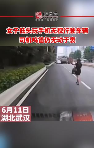 女子低头玩手机无视行驶车辆 司机鸣笛仍无动于衷