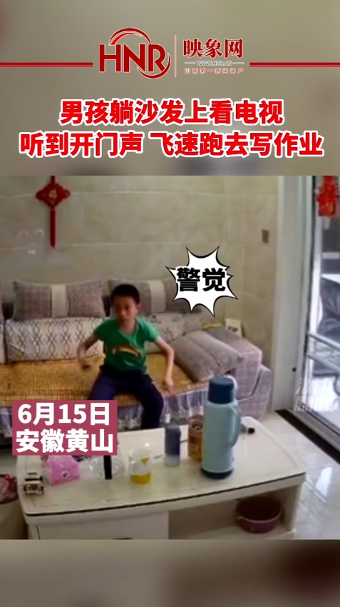 男孩躺沙发上看电视 听到开门声飞速跑去写作业