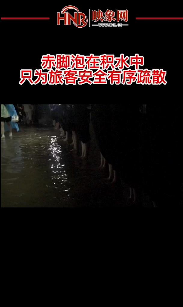 郑州车站工作人员手持应急灯，赤脚泡在积水中，只为安全有序疏散旅客