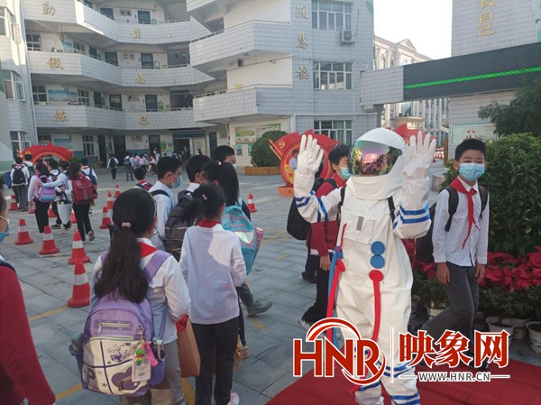 郑州小学生入学首日 老师着“航天服”与返校学生击掌加油