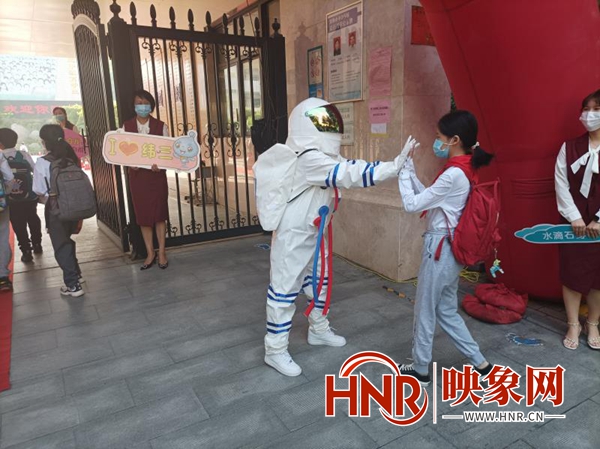 郑州小学生入学首日 老师着“航天服”与返校学生击掌加油