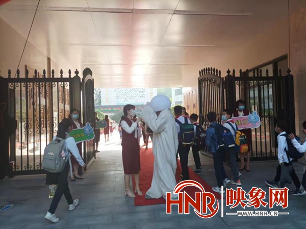 郑州小学生入学首日 老师着“航天服”与返校学生击掌加油